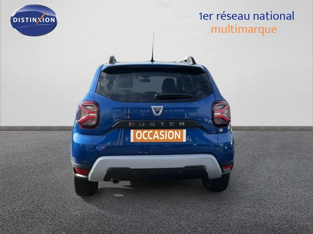 Vue arrière d'un Dacia Duster 2022 bleu Iron avec logo et feux arrière distinctifs, sur fond neutre.