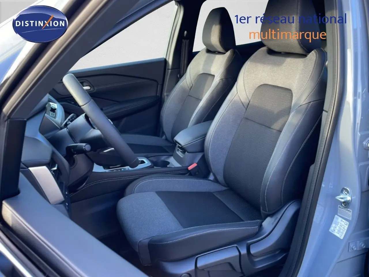 Vue intérieure côté conducteur du Nissan Qashqai 2025 gris argile, montrant les sièges tissu bicolore et le volant multifonction.