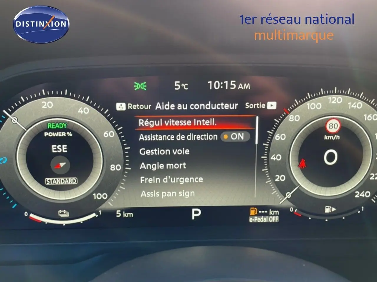 Tableau de bord numérique du Nissan Qashqai gris argile, affichant l'aide au conducteur et la vitesse à 0 km/h.