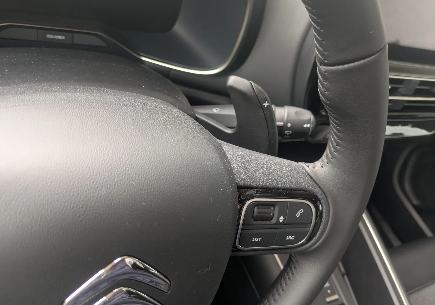 Gros plan sur le volant cuir noir du Citroën C5 Aircross hybride 2025 avec commandes audio intégrées.