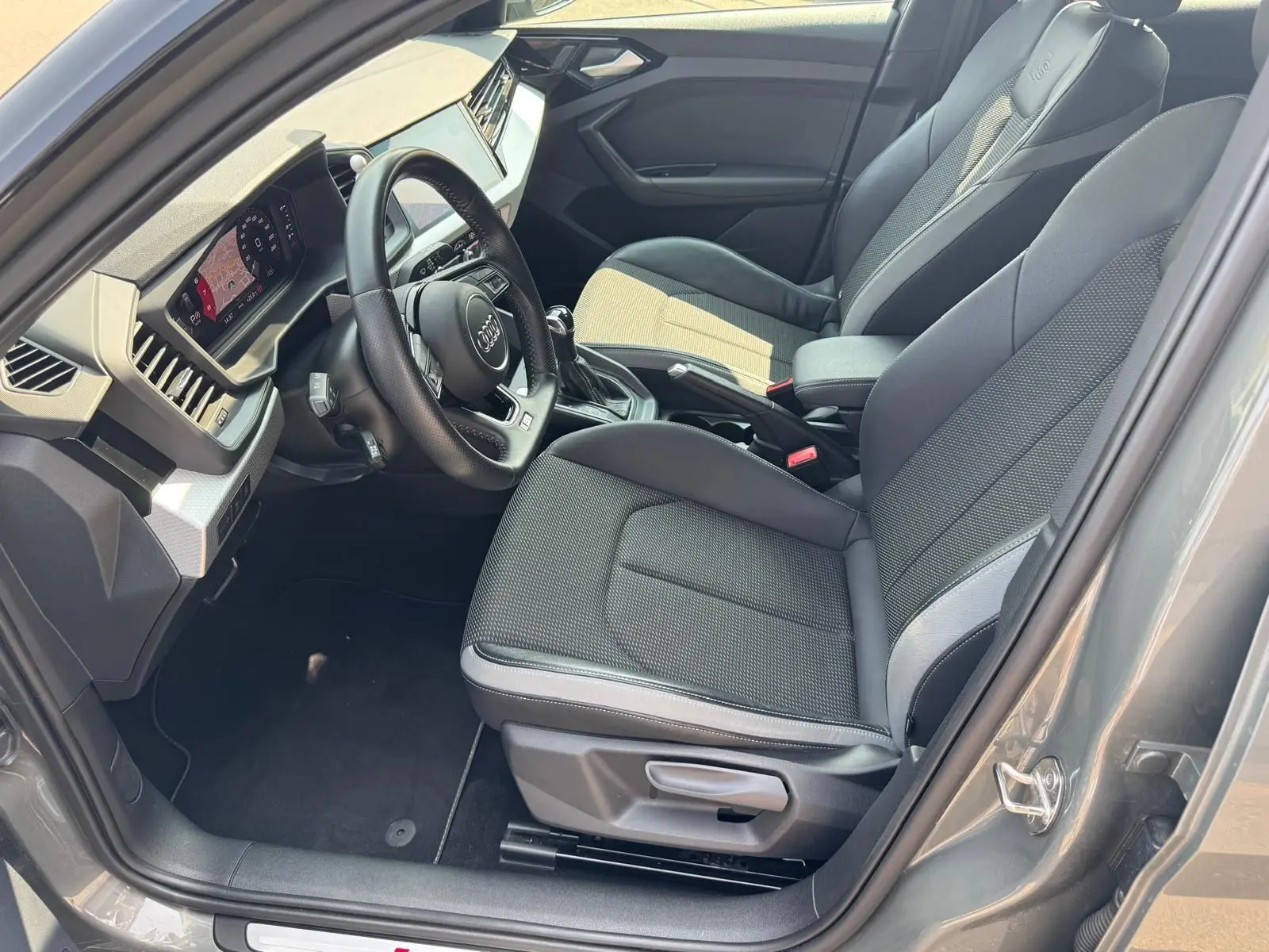 Intérieur gris de l'Audi A1 Sportback 2019, vue côté conducteur, volant multifonction et sièges sport en tissu et cuir.