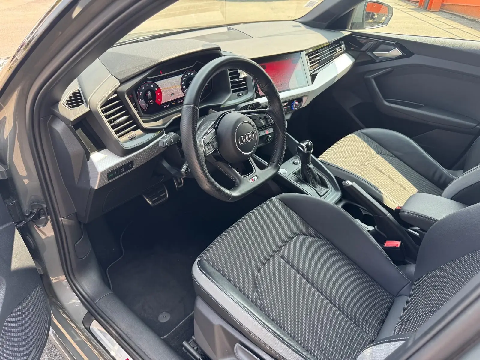 Intérieur gris de l'Audi A1 Sportback 2019 vu côté conducteur, avec tableau de bord numérique et volant sport.