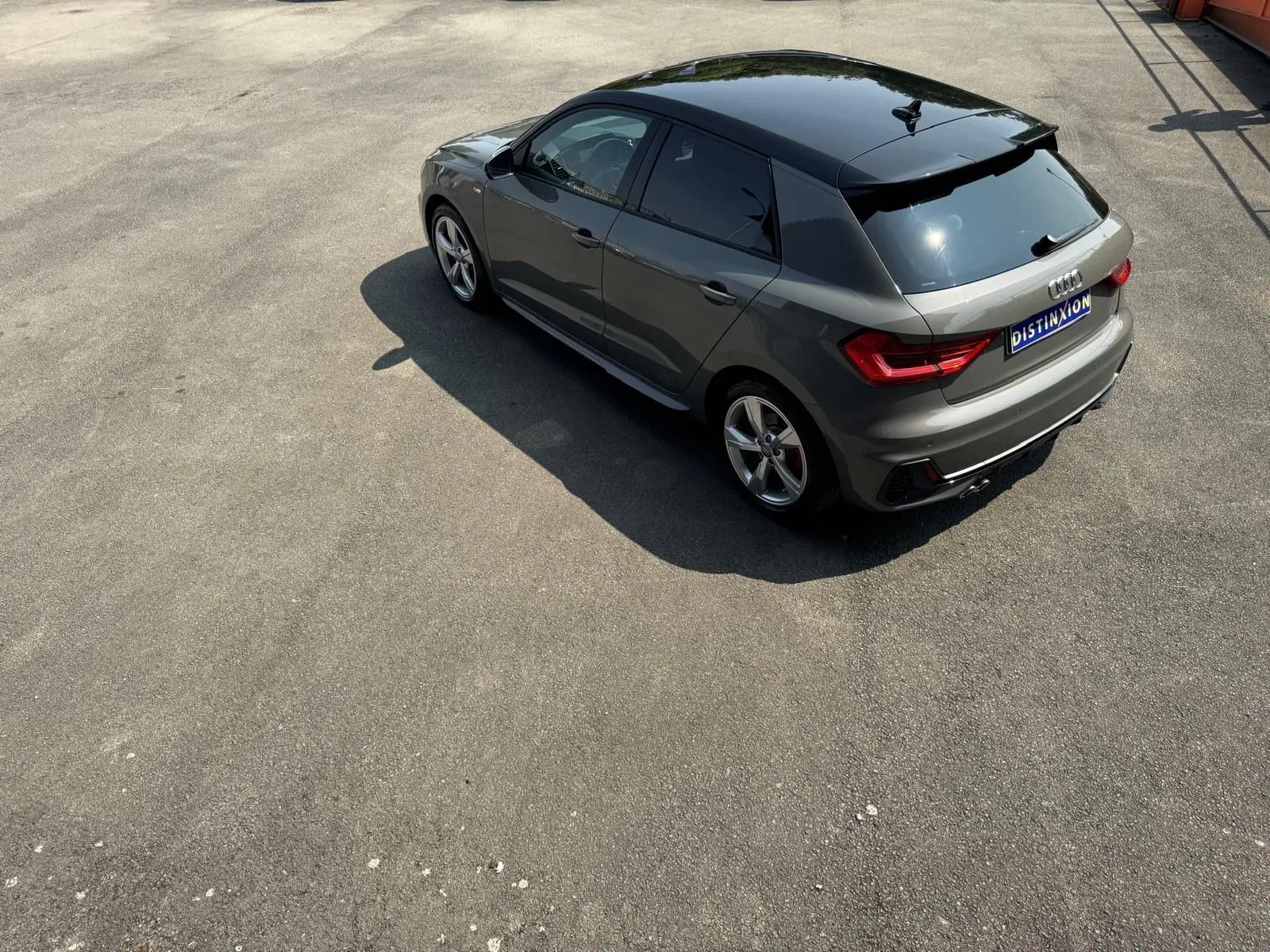 Audi A1 Sportback gris vue 3/4 arrière droit, avec toit noir brillant et jantes alliage sport.