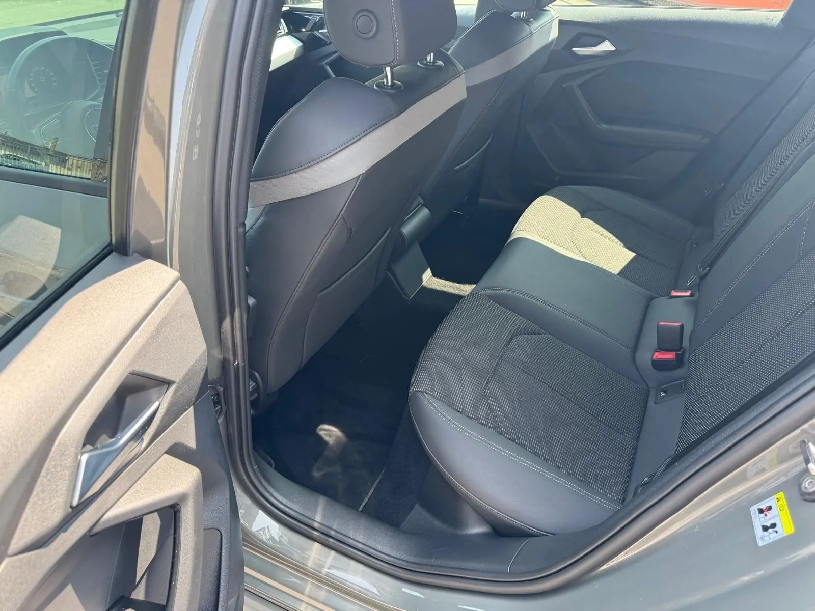 Vue intérieure arrière côté gauche de l'Audi A1 Sportback gris 2019, sièges en cuir noir et tissu perforé.