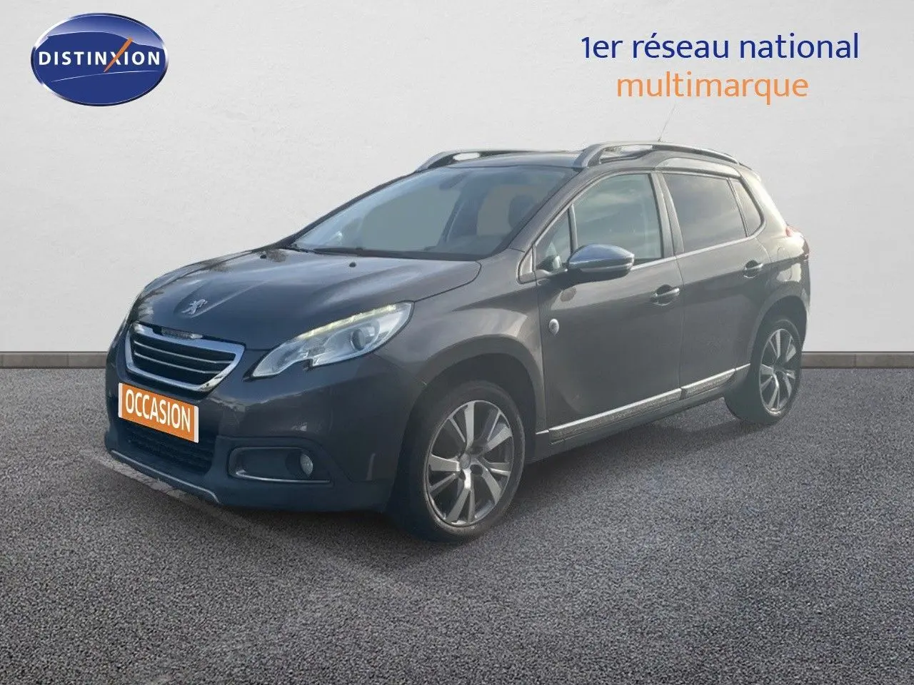 Peugeot 2008 gris platinium métal en 3/4 avant droit, avec jantes alliage et barres de toit visibles.