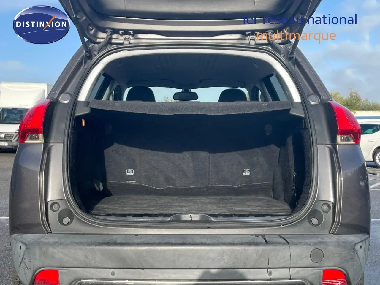 Coffre ouvert d'un Peugeot 2008 gris platinium métal, vue arrière montrant l'espace de chargement vide.