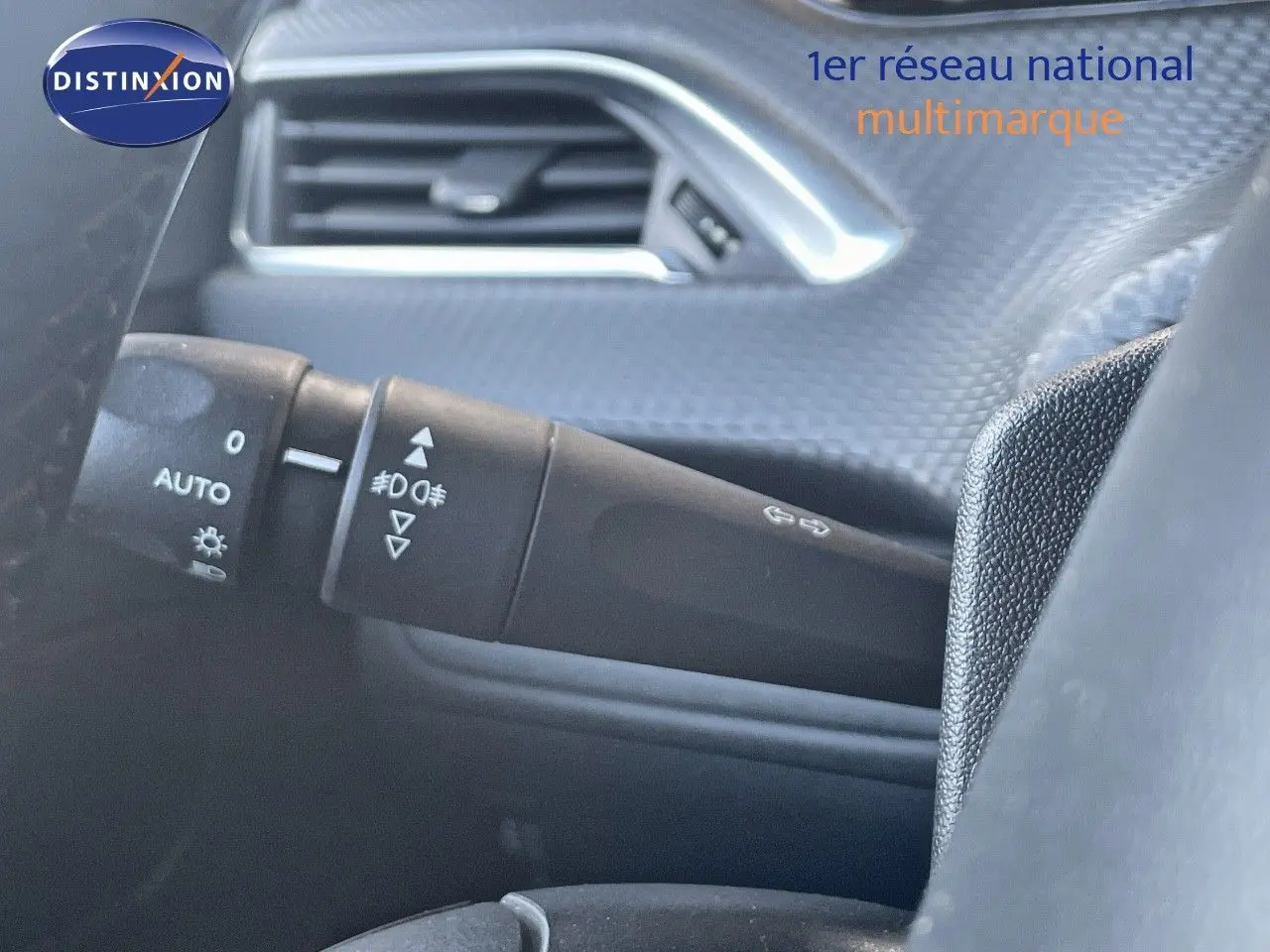 Gros plan sur la commande des phares et clignotants à gauche du volant dans l'habitacle d'un Peugeot 2008 gris platinium.
