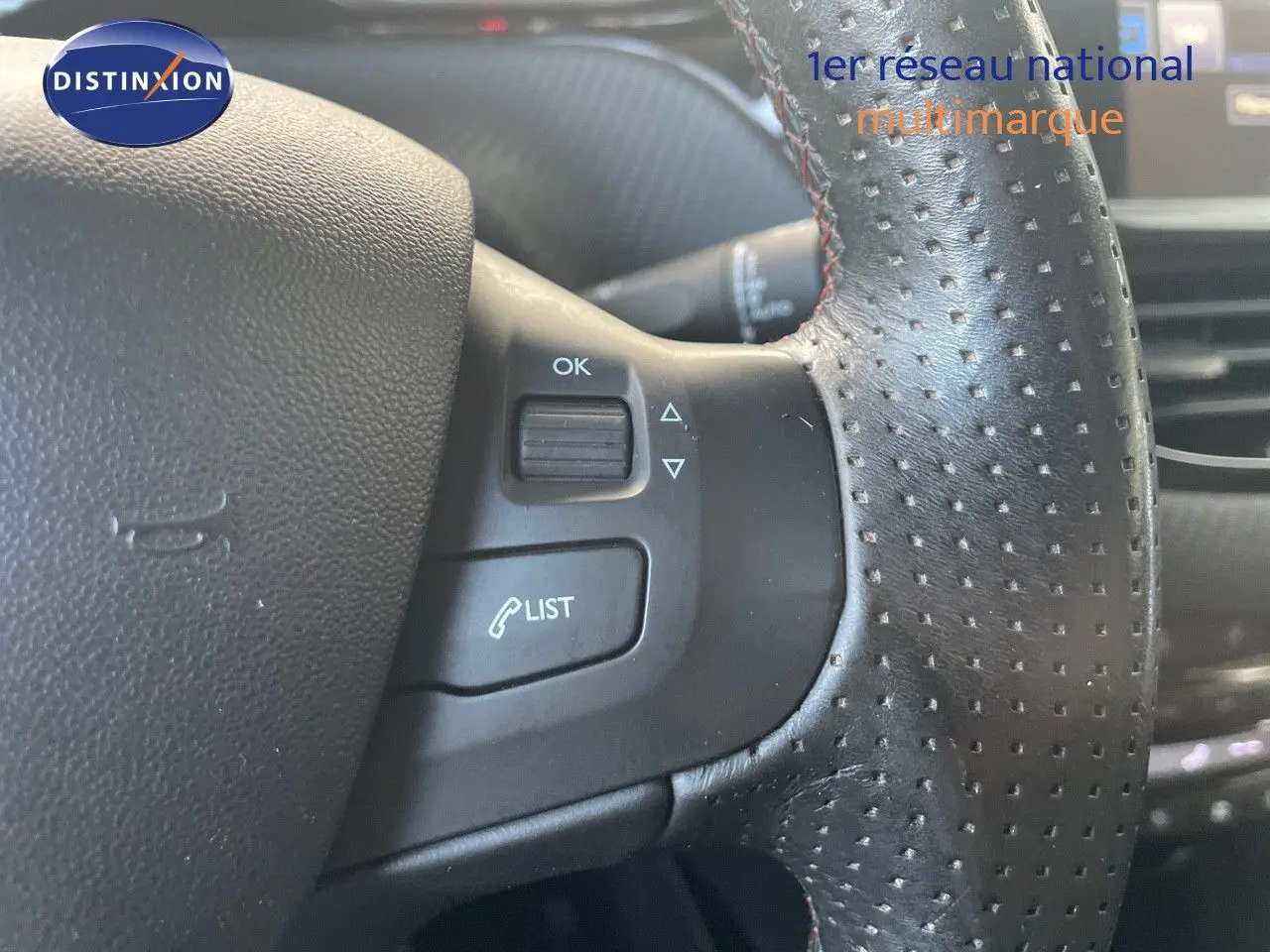 Gros plan sur le volant en cuir noir perforé du Peugeot 2008 1.2 PureTech 110ch Crossway gris platinium, avec commandes intégrées.