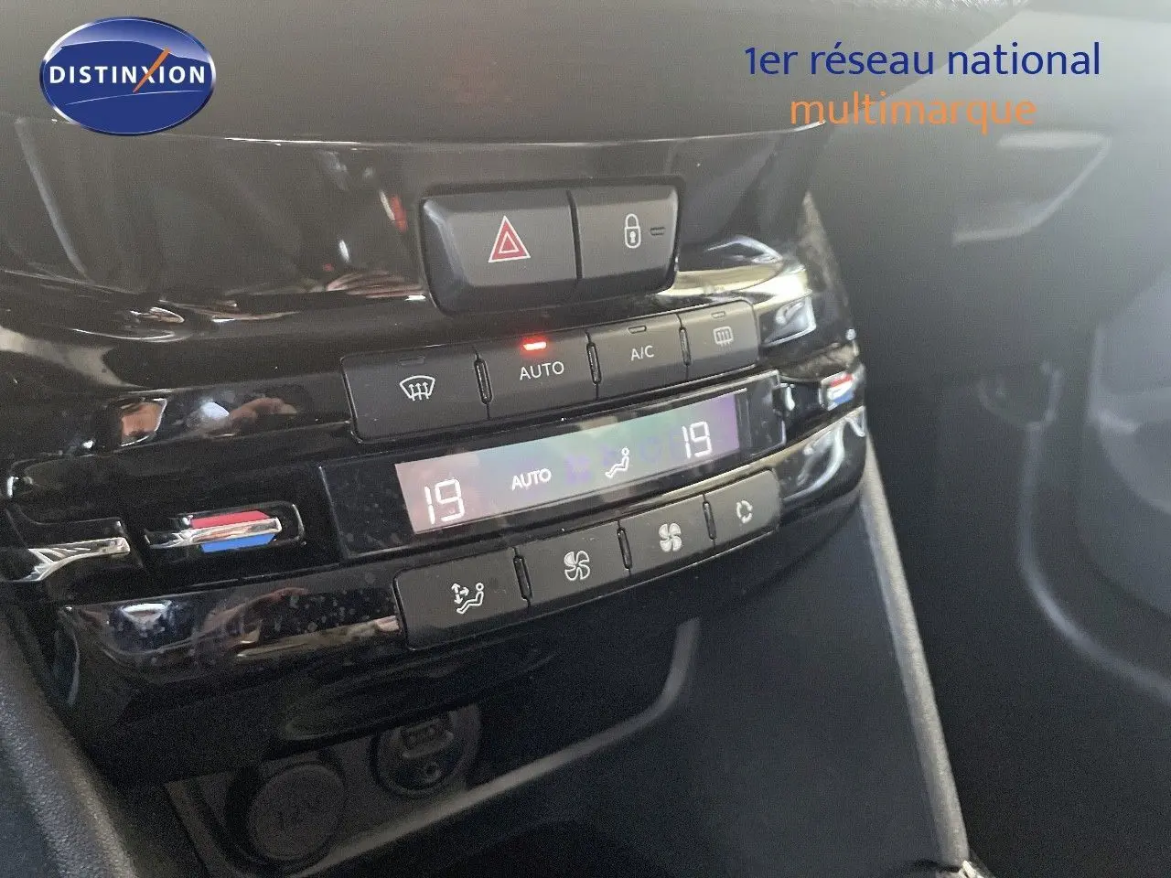 Gros plan sur la console centrale noire du Peugeot 2008 2019 montrant les commandes de climatisation automatique et les boutons d'alerte et verrouillage.