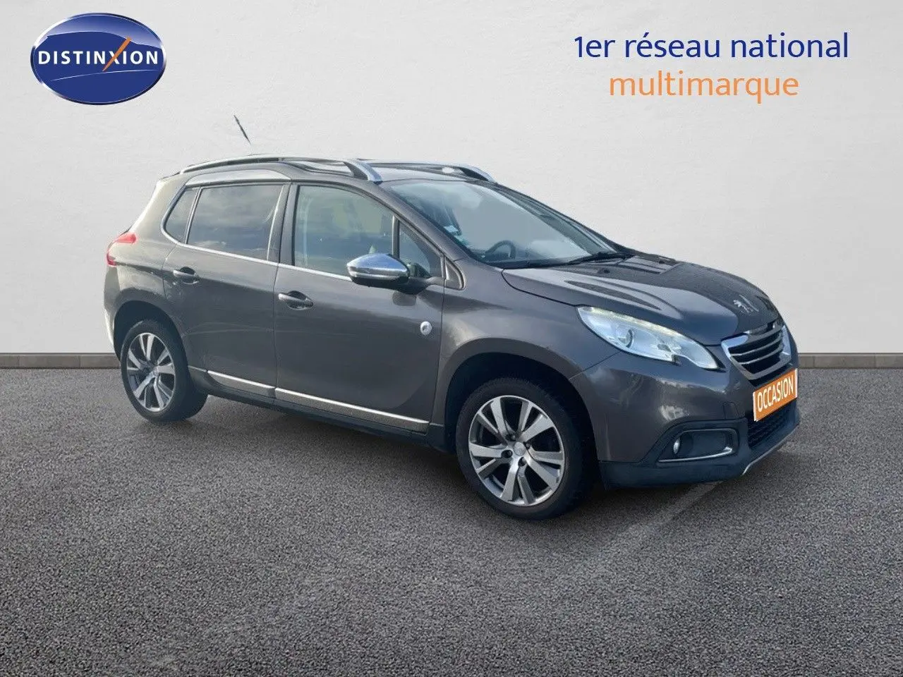 Peugeot 2008 gris platinium métal en 3/4 avant droit, avec jantes alliage et barres de toit visibles.