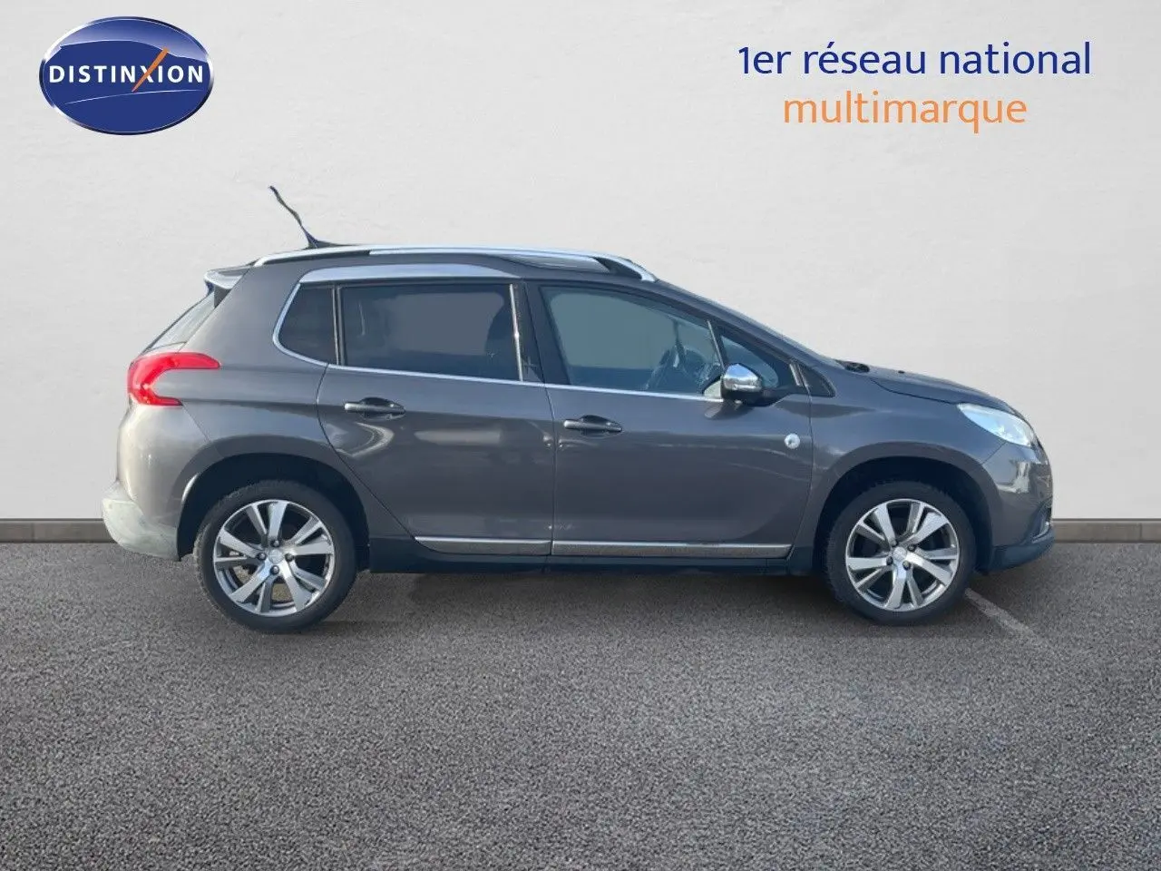 Profil côté gauche d'un Peugeot 2008 gris platinium métallisé de 2019 avec jantes alliage et barres de toit.