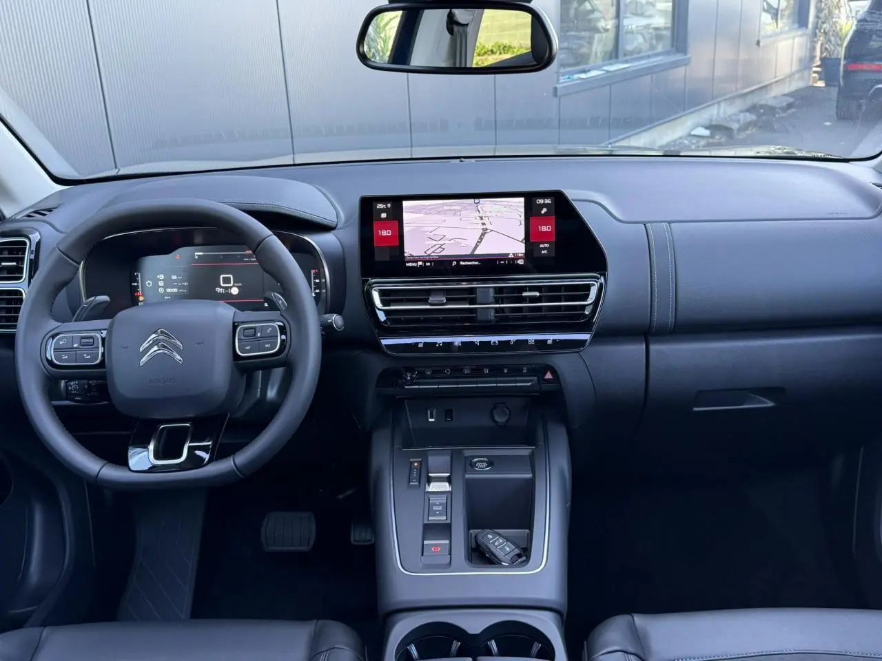 Intérieur noir du Citroën C5 Aircross 2025 vu de face, tableau de bord moderne avec écran tactile central et volant multifonction.