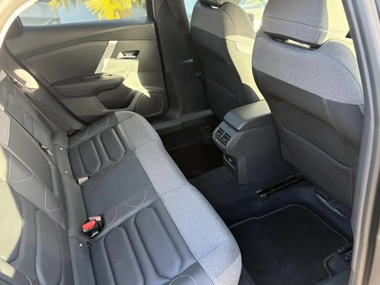 Vue intérieure arrière côté droit de la Citroën C4 2024, sièges bicolores gris et noir avec accoudoir central.