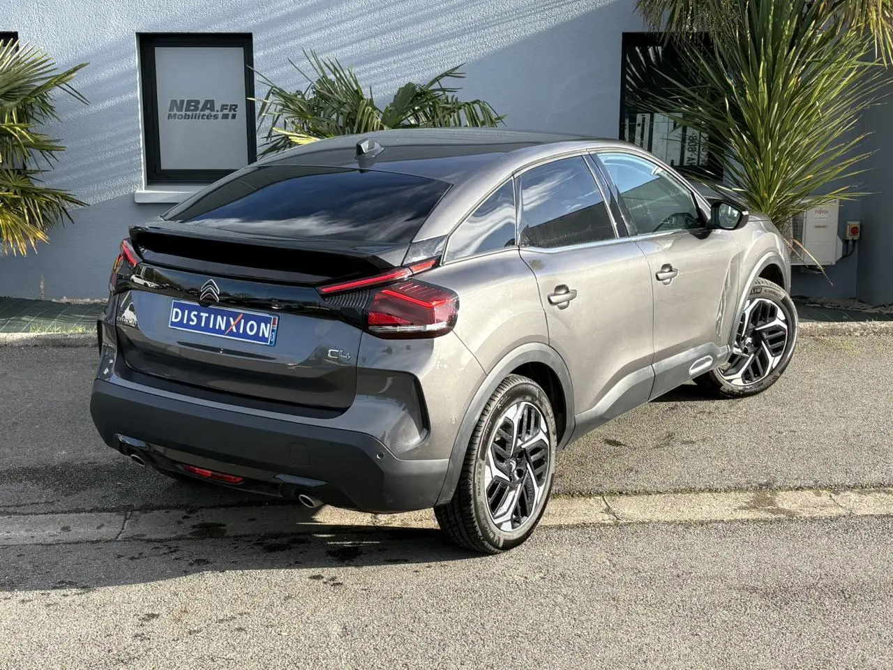 Vue 3/4 arrière droite d'une Citroën C4 2024 gris Platinium avec jantes alliage 18'' et toit noir brillant.