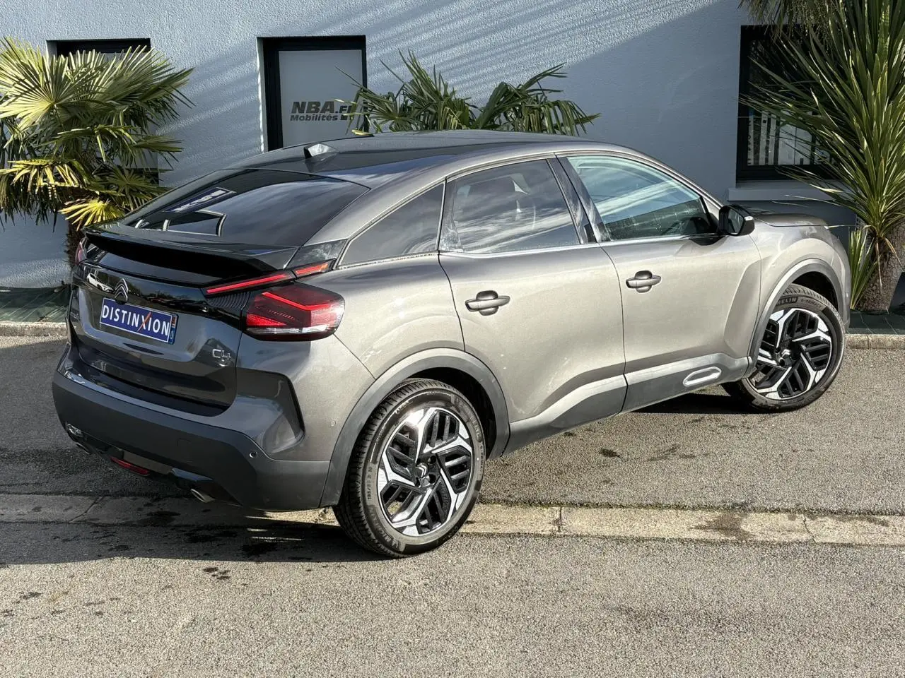 Vue 3/4 arrière droite d'une Citroën C4 2024 gris Platinium avec jantes alliage 18'' et toit noir brillant.