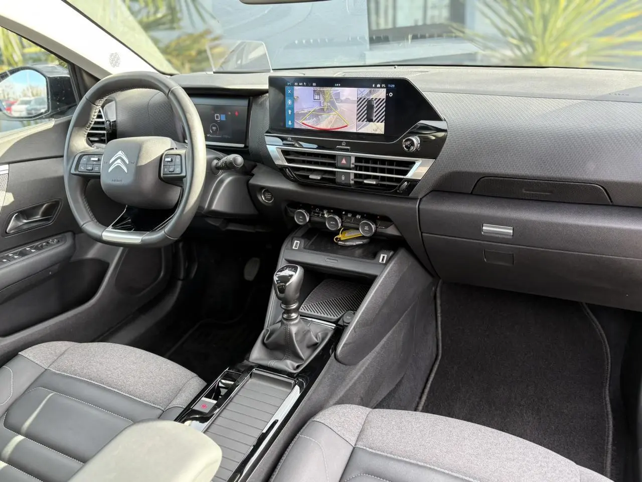 Vue intérieure côté conducteur de la Citroën C4 2024, montrant le volant cuir, écran tactile 10" et levier de vitesses manuel.