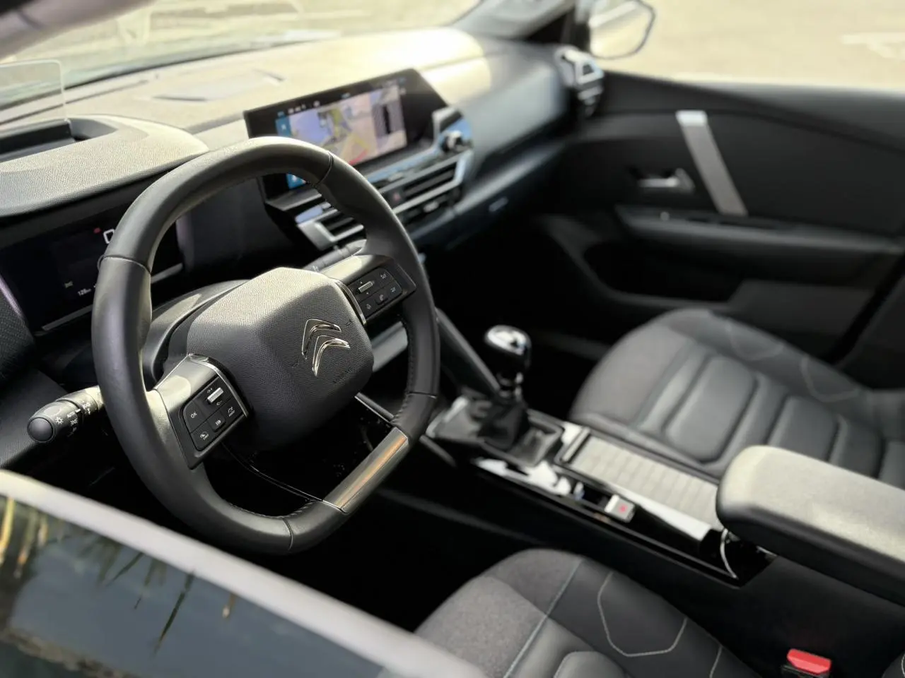 Vue intérieure côté conducteur de la Citroën C4 2024 gris Platinium, avec volant multifonction et écran tactile GPS 10 pouces.