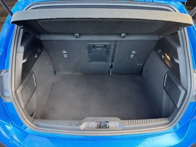 Coffre ouvert vu de l'arrière d'une Ford Focus 1.5 EcoBoost 150ch ST-Line BVA 2022 bleu, intérieur noir et espace de chargement vide.