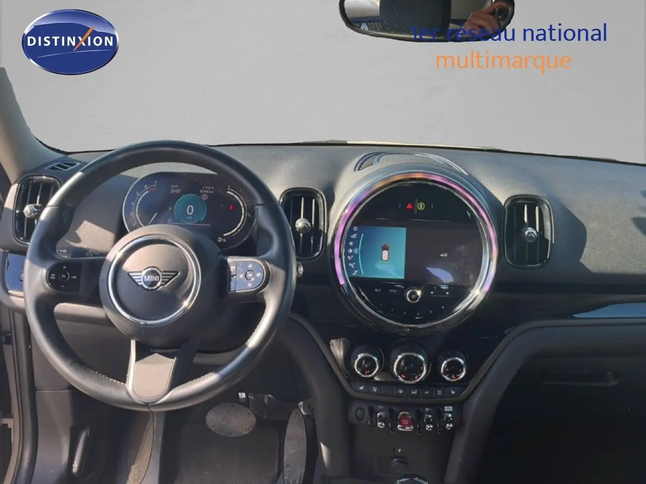 Vue intérieure frontale du tableau de bord et volant noir du MINI Countryman 2023, avec écran central rond allumé.
