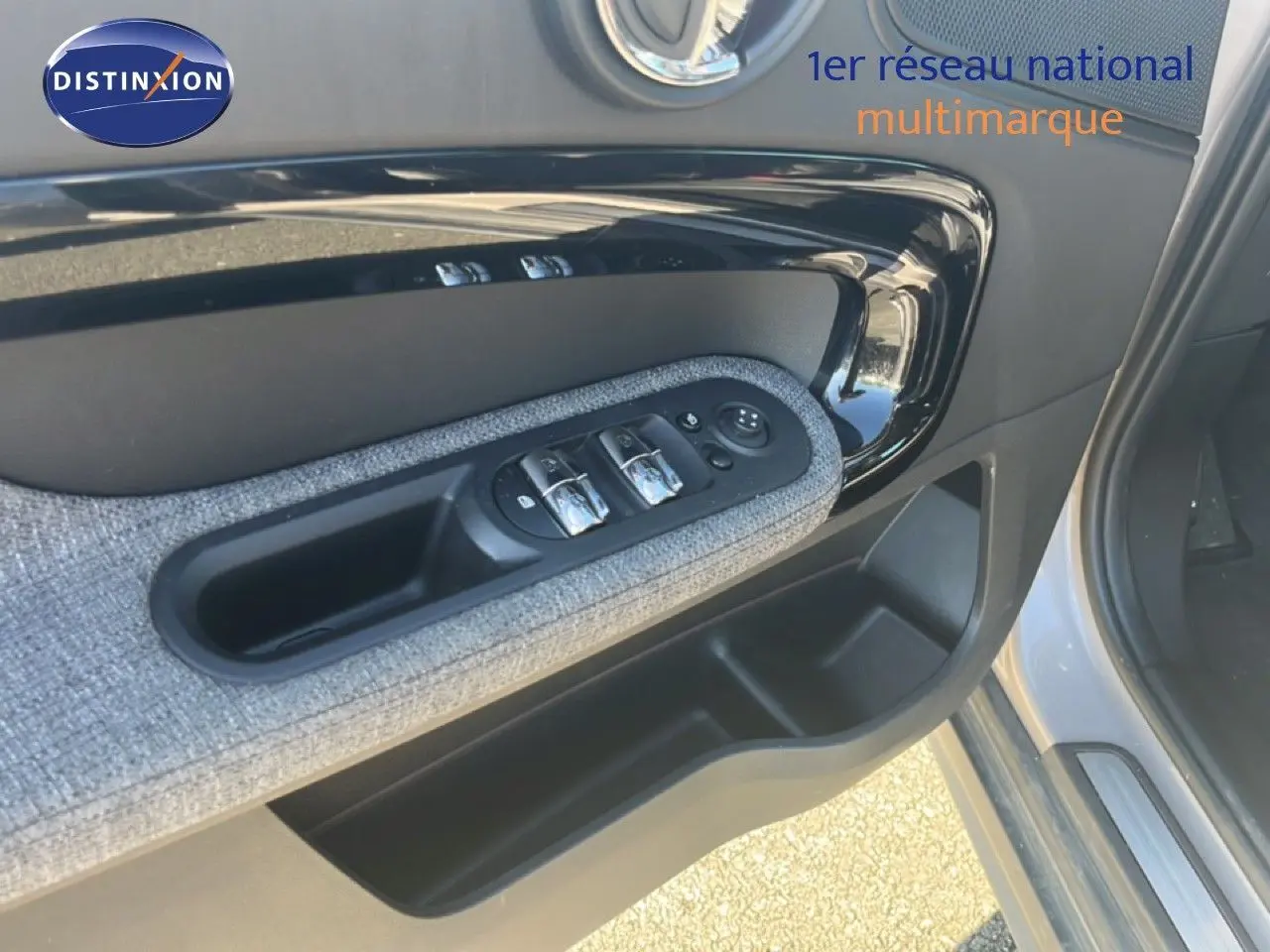 Gros plan sur la porte avant gauche de la MINI Countryman 2023 en rooftop grey, avec commandes de vitres et habillage tissu.