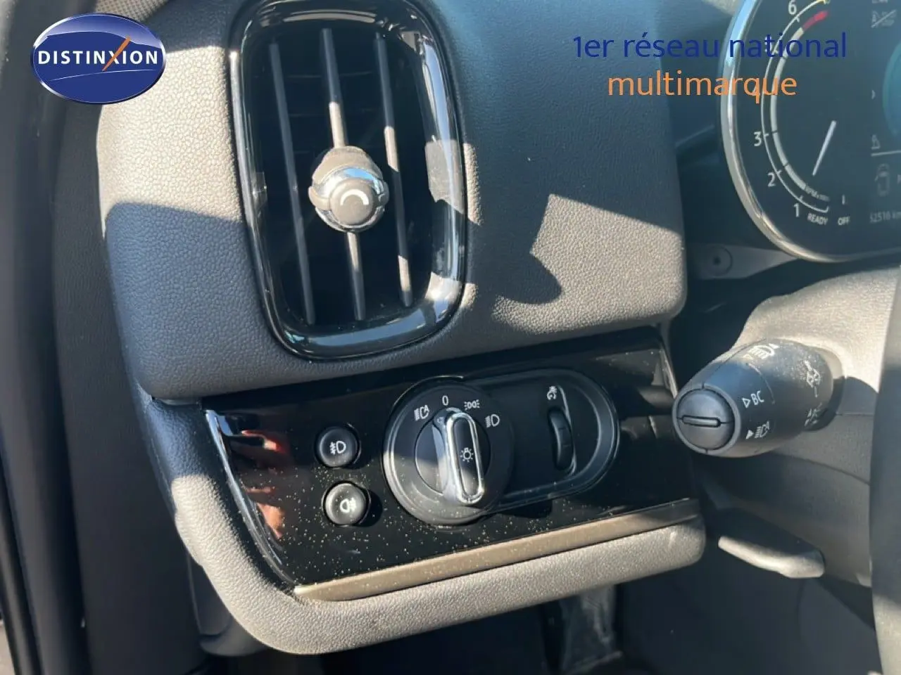 Détail du tableau de bord côté gauche du MINI Countryman Cooper 2023 en rooftop grey, montrant les commandes d'éclairage et la sortie d'air.