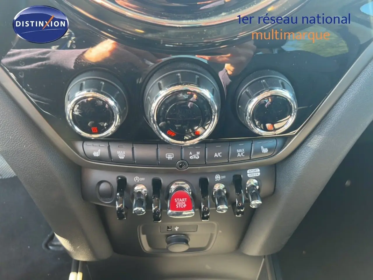 Gros plan sur la console centrale du MINI Countryman 2023, mettant en valeur les commandes de climatisation et le bouton start/stop rouge.