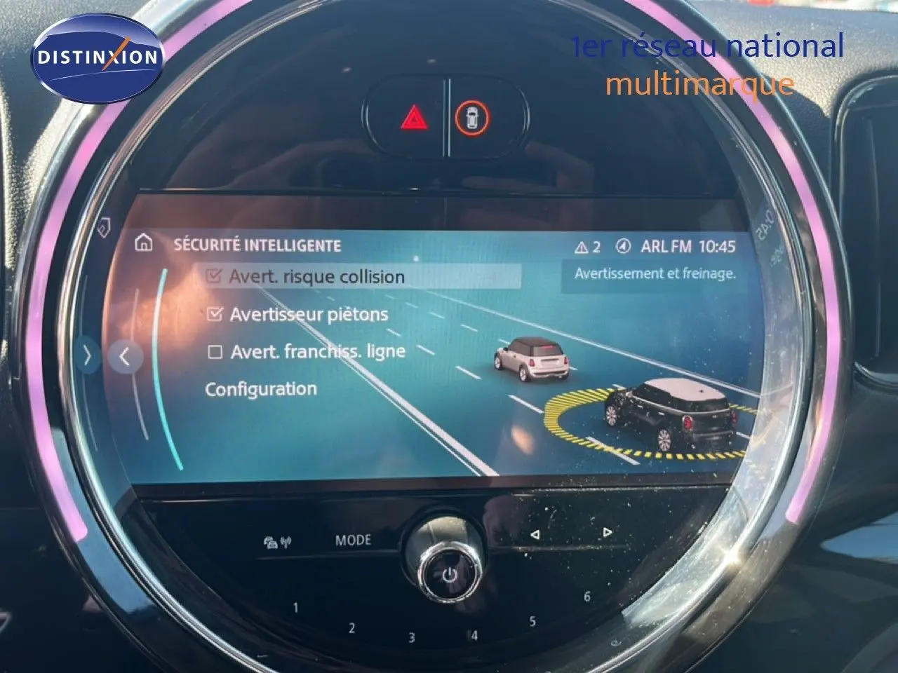 Écran central rond du MINI Countryman 2023 affichant les options de sécurité intelligente, avec éclairage LED rose autour.