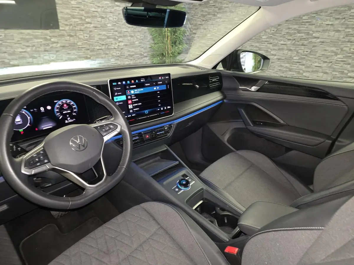 Vue intérieure côté conducteur du Volkswagen Tiguan 2025 avec tableau de bord numérique et sellerie tissu grise.