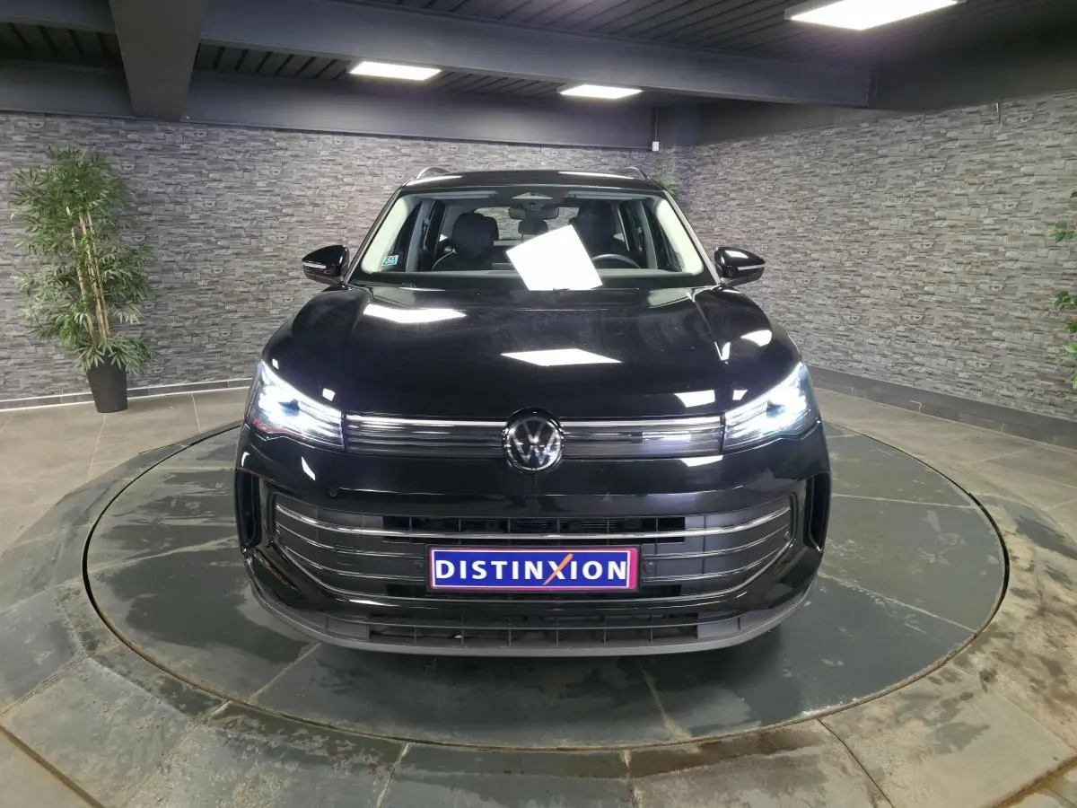 Volkswagen Tiguan noir 2025 vue de face avec phares LED allumés dans un showroom fermé.
