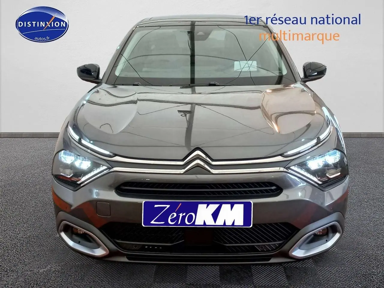 Vue de face d'une Citroën C4 X gris platinium métal avec feux LED allumés et calandre chromée distinctive.