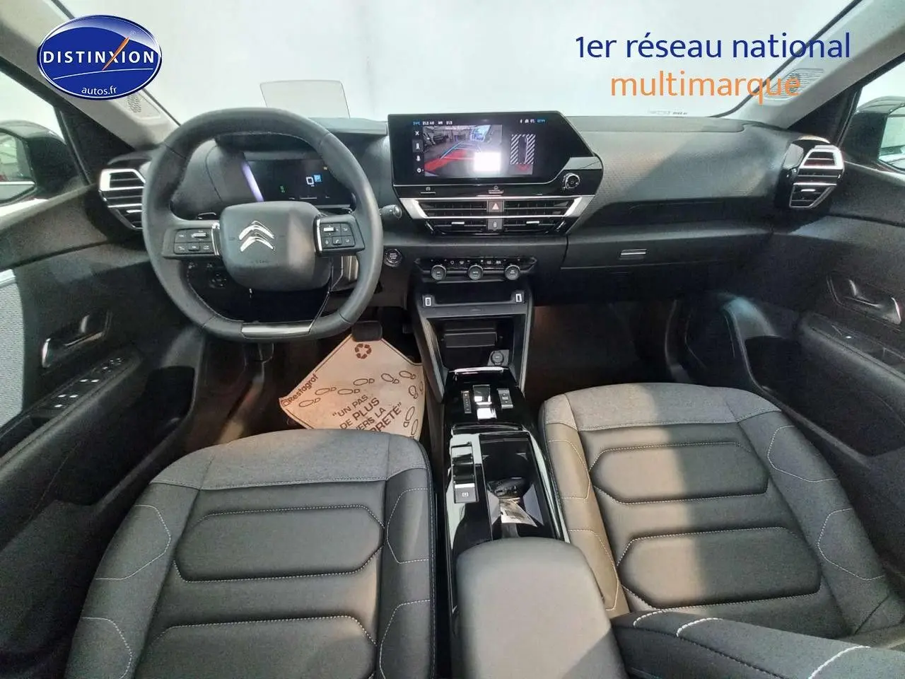 Intérieur avant de la Citroën C4 X 2023, vue centrée sur le tableau de bord et les sièges en cuir noir.