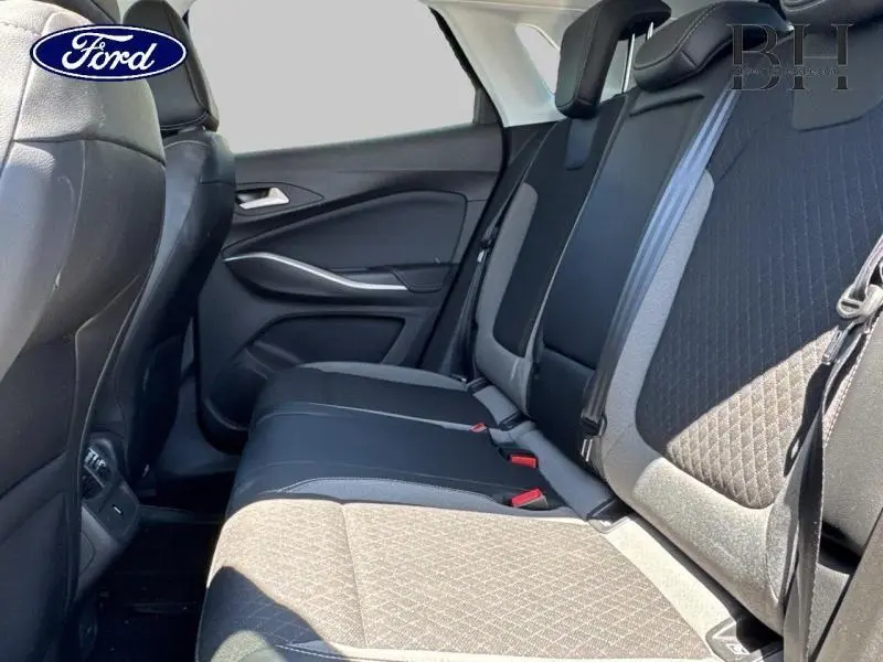 Vue latérale intérieure arrière montrant les sièges en tissu noir et gris avec ceintures de sécurité.