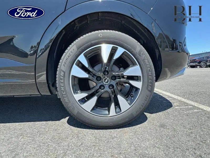 Gros plan sur la jante alu bi-ton argent et noir côté arrière gauche d’un Opel Grandland noir diamant métallisé.