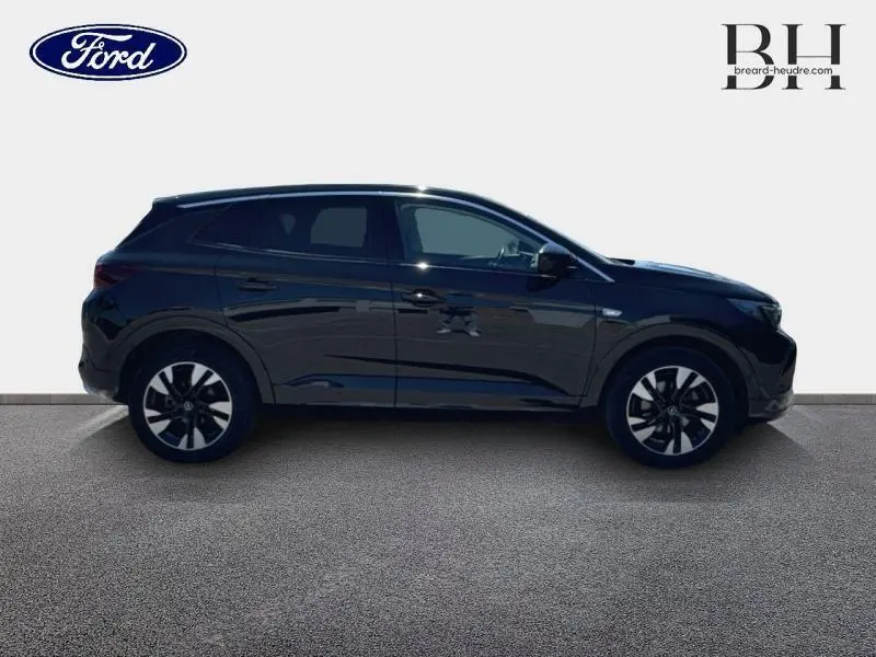 Profil droit d'un Opel Grandland noir diamant métallisé avec jantes alu bi-ton argent et noir, vue extérieure claire.