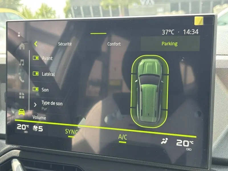 Écran tactile du tableau de bord affichant l'aide au stationnement du Dacia Bigster blanc en vue aérienne.