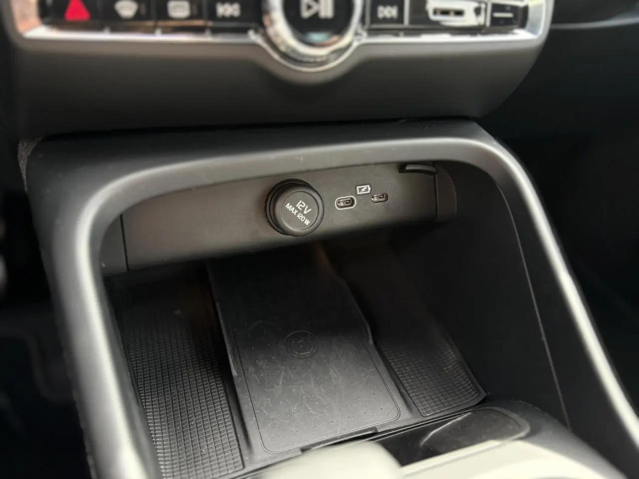 Détail de la console centrale du Volvo XC40 2024 noir Onyx montrant prise 12V et ports USB-C avec recharge sans fil.