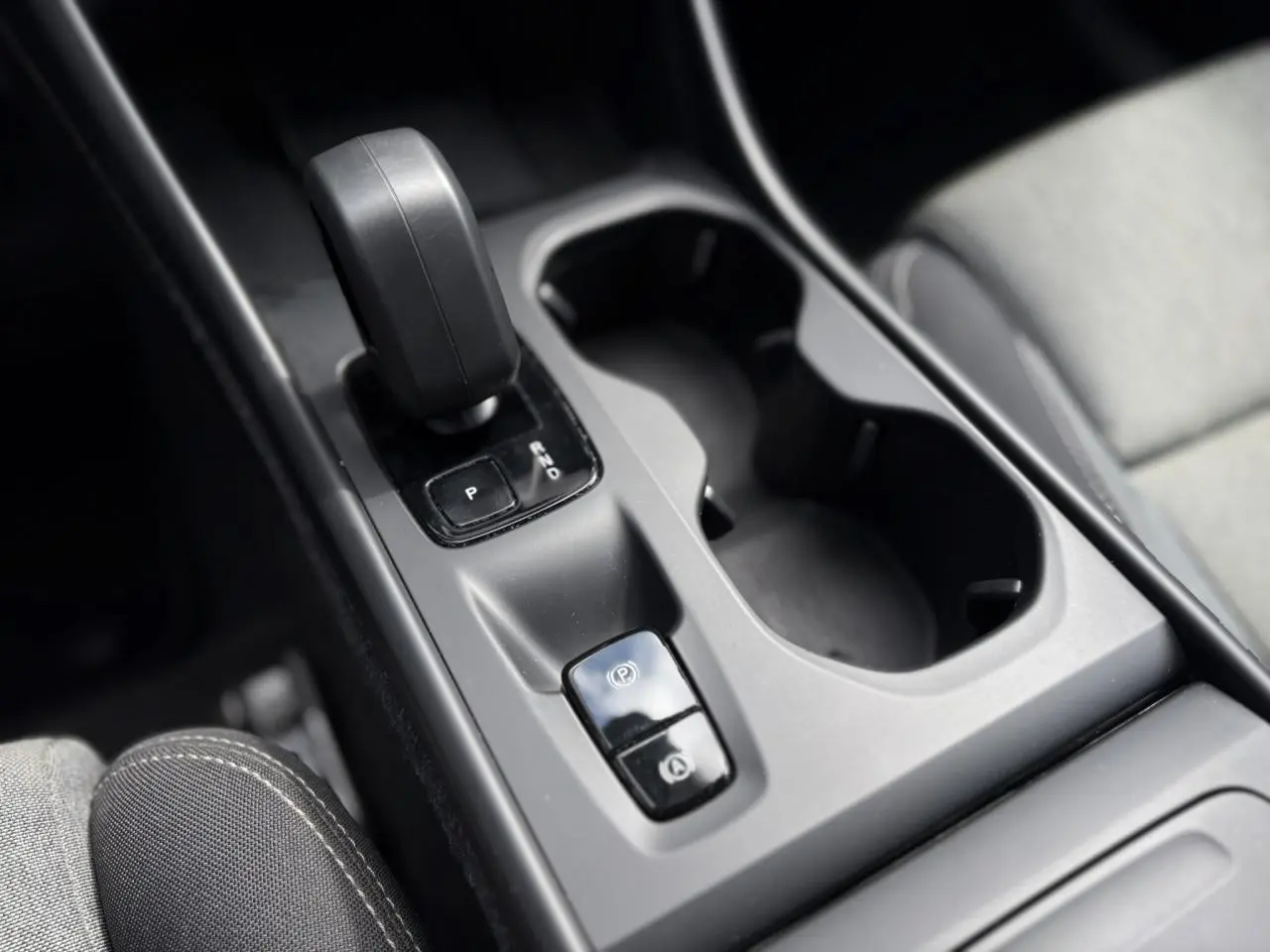 Gros plan sur la console centrale du Volvo XC40 2024, montrant le levier de vitesses et les porte-gobelets noirs.