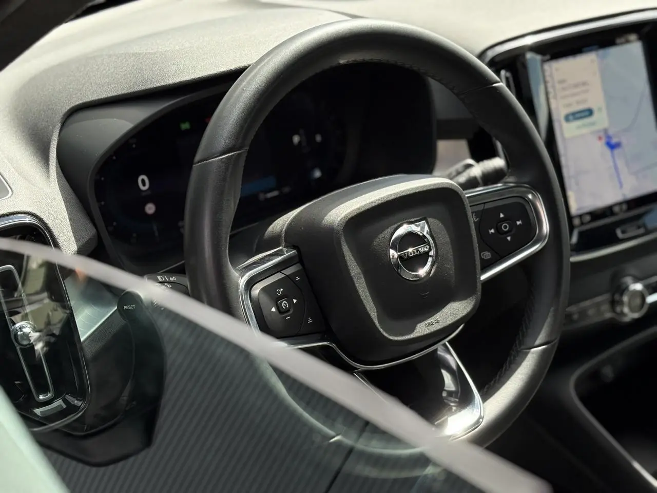 Vue rapprochée du volant noir du Volvo XC40 2024, avec tableau de bord digital et écran tactile central visible.