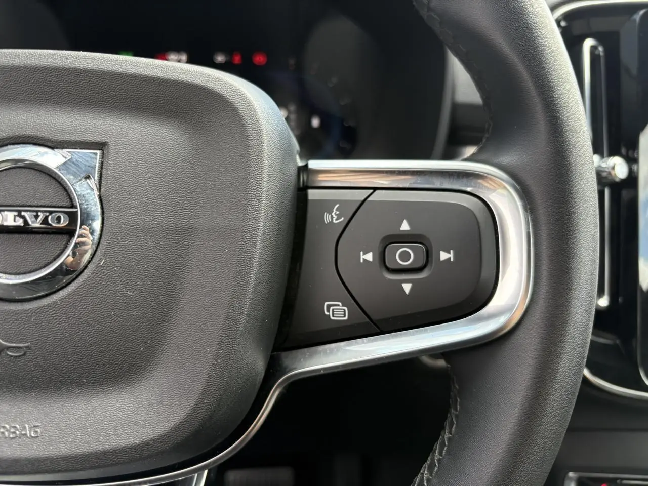 Gros plan sur le volant noir du Volvo XC40 2024 montrant les commandes multifonctions côté droit avec insert chromé.
