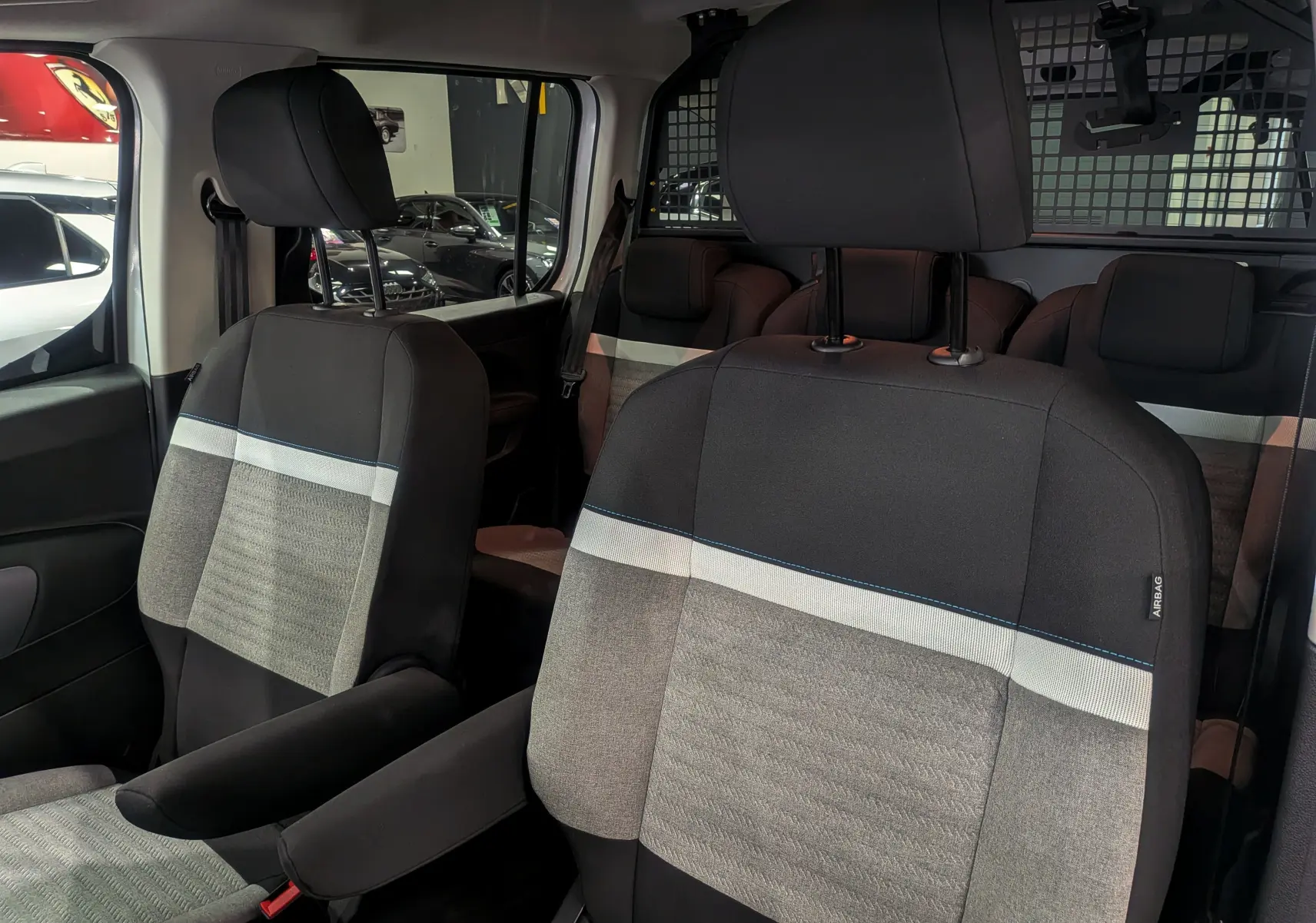 Gros plan sur les sièges avant en tissu gris et noir du Citroën Berlingo Blanc Glacier, version utilitaire avec séparation métallique.