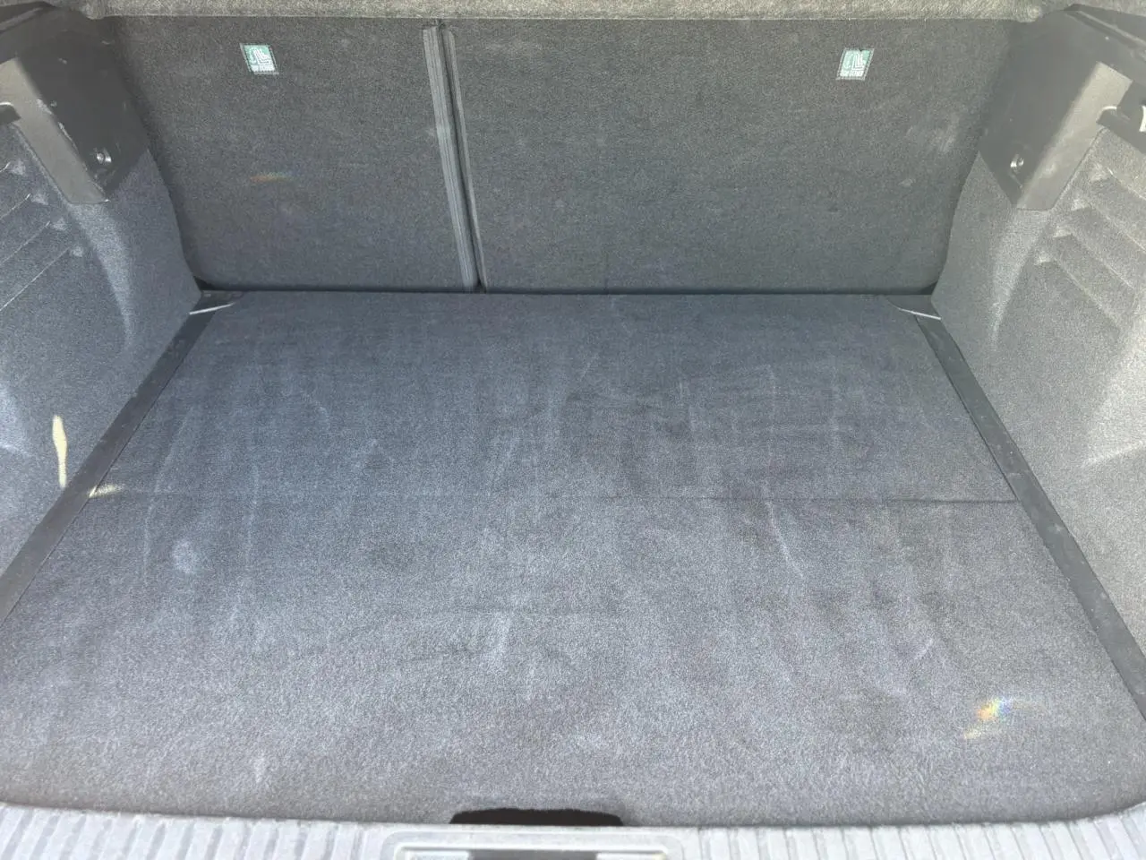 Vue intérieure du coffre spacieux et propre du Renault Symbioz E-Tech Full Hybrid 145 Iconic, revêtement gris foncé.