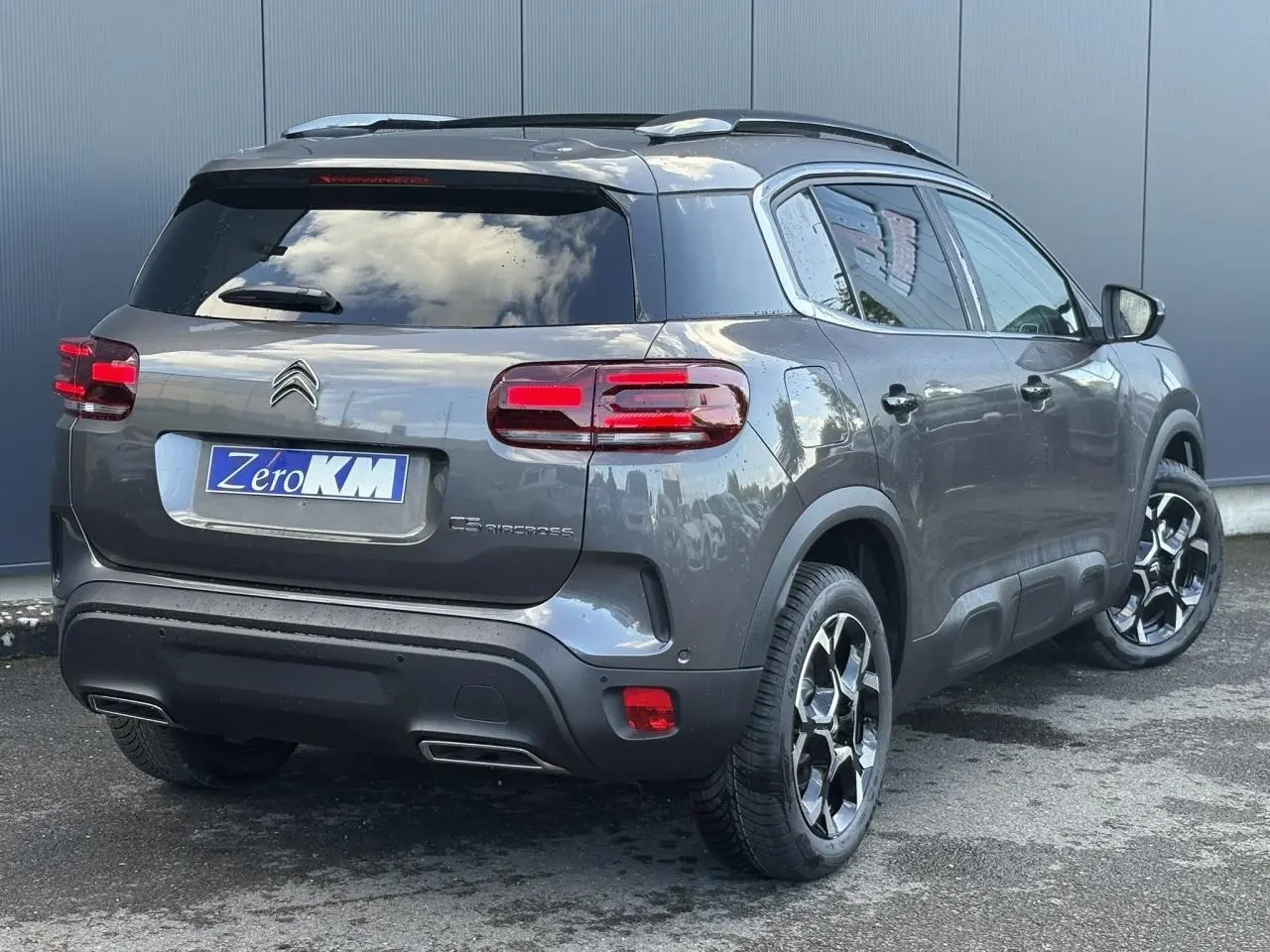 Vue 3/4 arrière droite d'un Citroën C5 Aircross gris Platinium avec jantes alliage bi-ton et hayon électrique.
