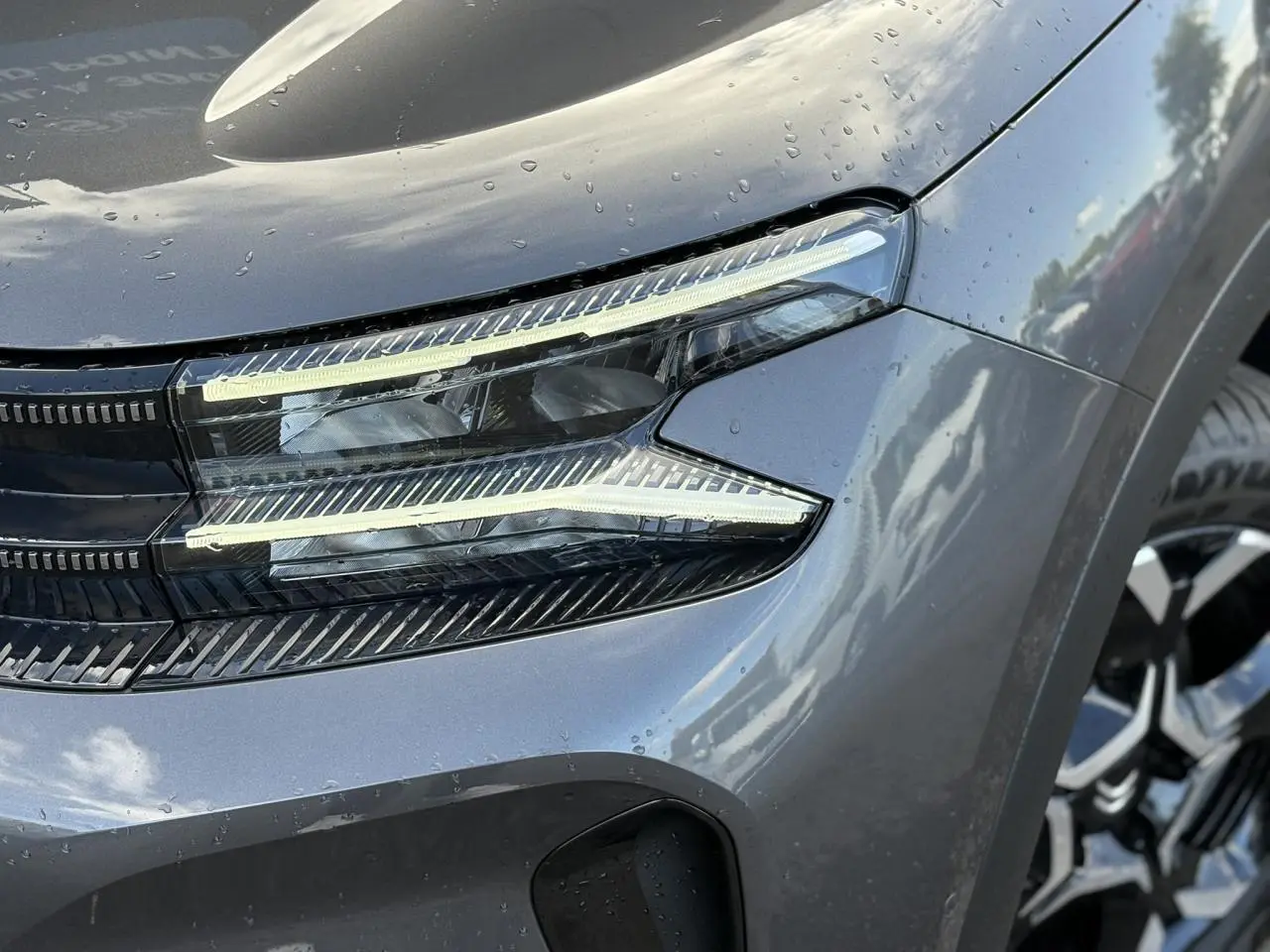 Gros plan sur le phare avant droit et la jante alliage 18'' gris platinium du Citroën C5 Aircross 2025