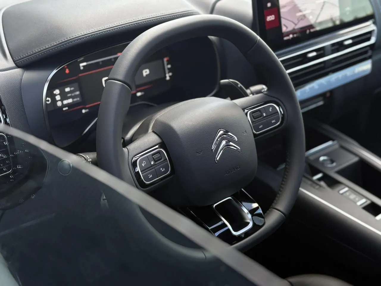 Vue rapprochée du volant noir de la Citroën C5 Aircross 2025 avec commandes intégrées et tableau de bord numérique.