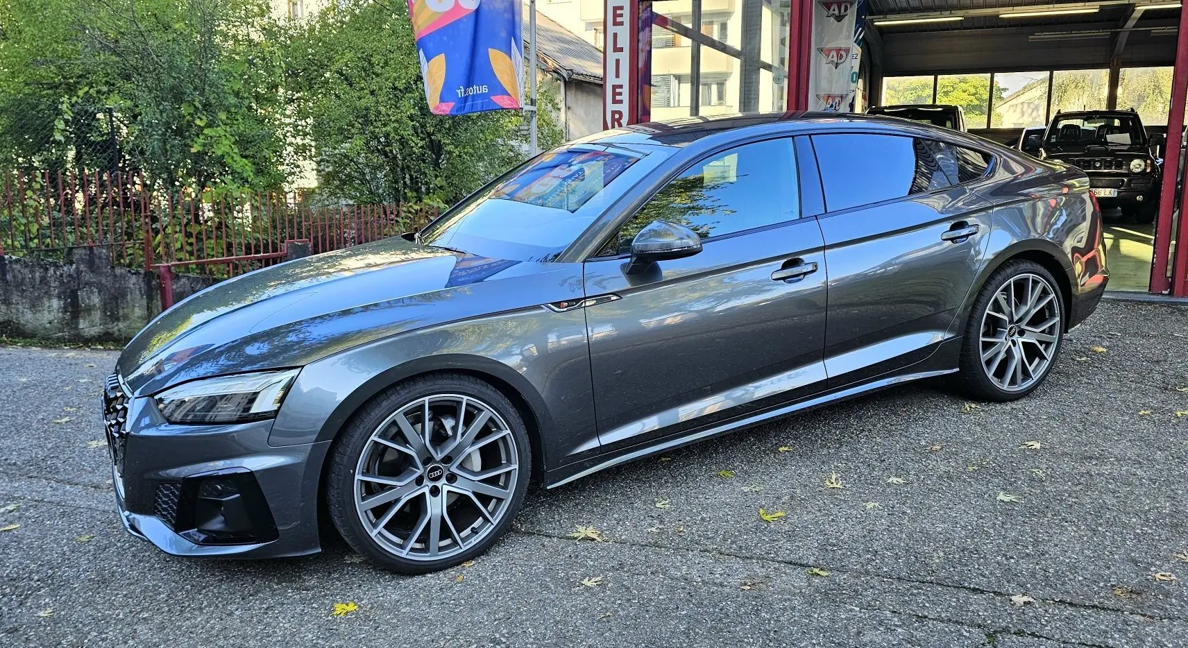 Audi A5 Sportback gris Daytona vue de côté droit en extérieur, avec jantes alliage et calandre s line.