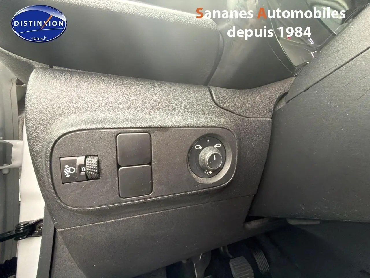 Détail des commandes d'éclairage côté gauche du tableau de bord noir d'une Citroën C3 2021 blanche toit rouge.