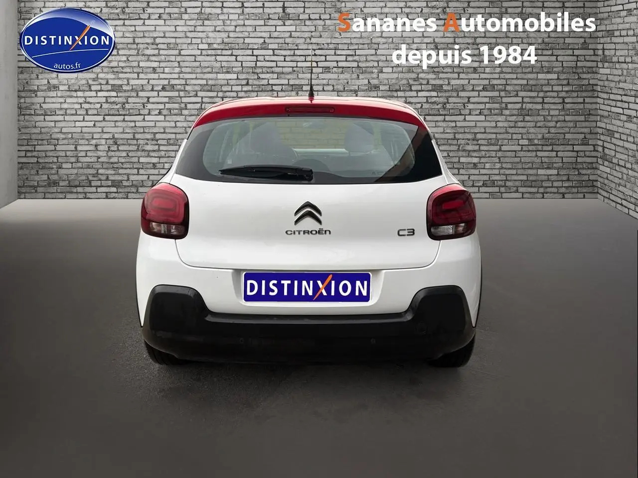 Vue arrière d'une Citroën C3 2021 blanche avec toit rouge, feux arrière foncés et logo distinctif Citroën.