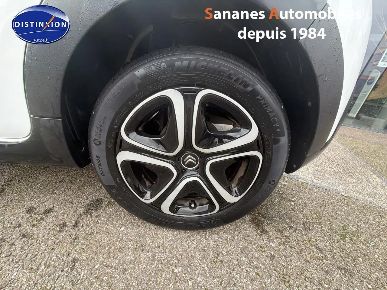 Gros plan sur la roue avant droite d'une Citroën C3 blanc toit rouge avec jante 16 pouces noire et argentée.