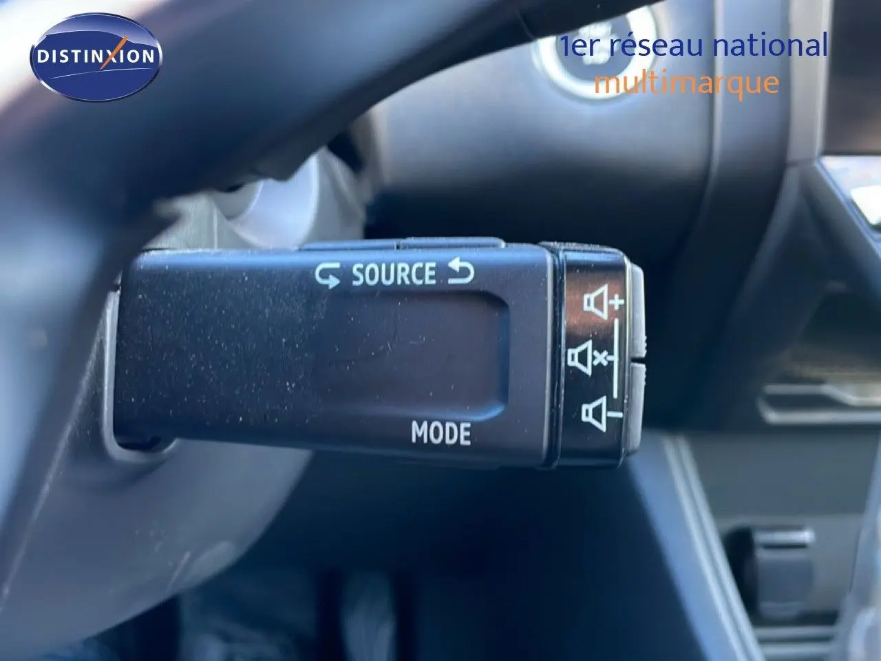 Gros plan sur la commande au volant du Renault Captur rouge Désir Métal, mettant en valeur les boutons source et mode.