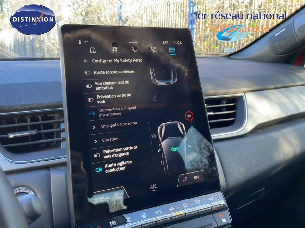 Vue rapprochée de l'écran tactile central du tableau de bord du Renault Captur rouge désir métal avec toit noir, affichant les aides à la conduite.